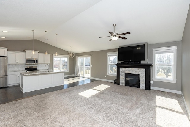 unfurnished living room with vaulted ceiling, ceiling fan, sink, and dark colored carpet