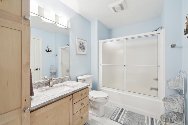 full bathroom with tile patterned flooring, vanity, shower / bath combination with glass door, and toilet