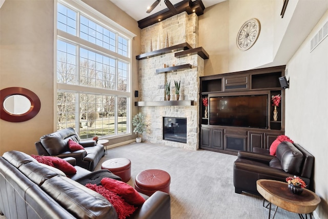 living room with a stone fireplace, carpet floors, and a high ceiling