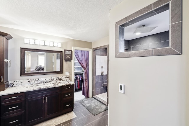 bathroom with vanity, a textured ceiling, and tiled shower