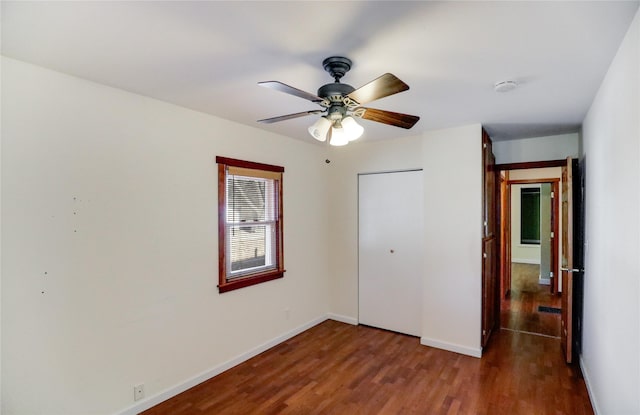 unfurnished bedroom featuring ceiling fan, dark hardwood / wood-style flooring, and a closet