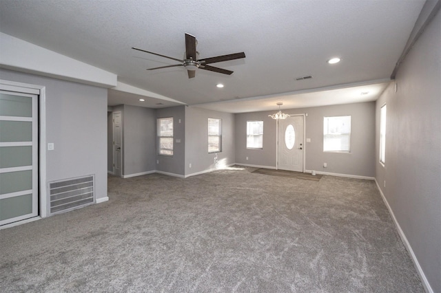 unfurnished living room featuring carpet, ceiling fan with notable chandelier, and a textured ceiling