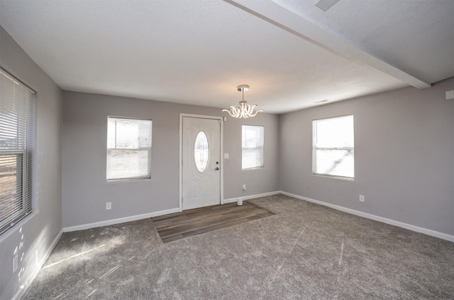 foyer entrance with beam ceiling, carpet floors, and a chandelier