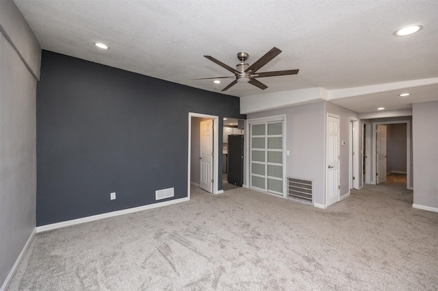 spare room featuring light colored carpet, a textured ceiling, and ceiling fan