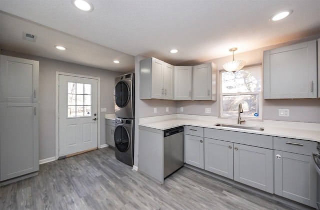 kitchen with stacked washer and dryer, sink, gray cabinets, dishwasher, and pendant lighting