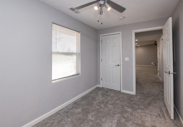 unfurnished bedroom featuring ceiling fan and dark colored carpet