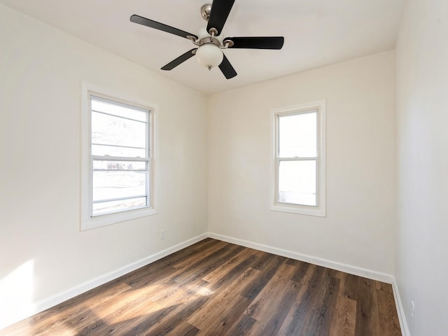 spare room featuring dark wood-type flooring, ceiling fan, and a healthy amount of sunlight