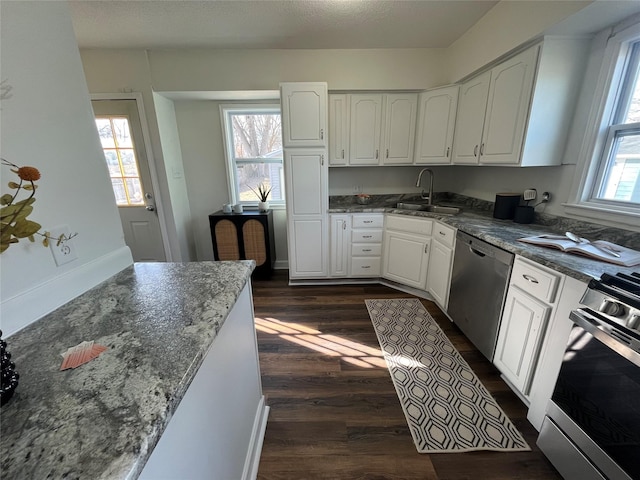 kitchen featuring white cabinetry, sink, dark stone counters, and appliances with stainless steel finishes