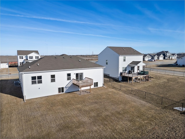 rear view of property featuring a wooden deck and a lawn