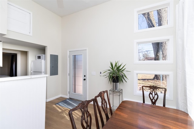 dining area featuring ceiling fan, a towering ceiling, wood-type flooring, and electric panel