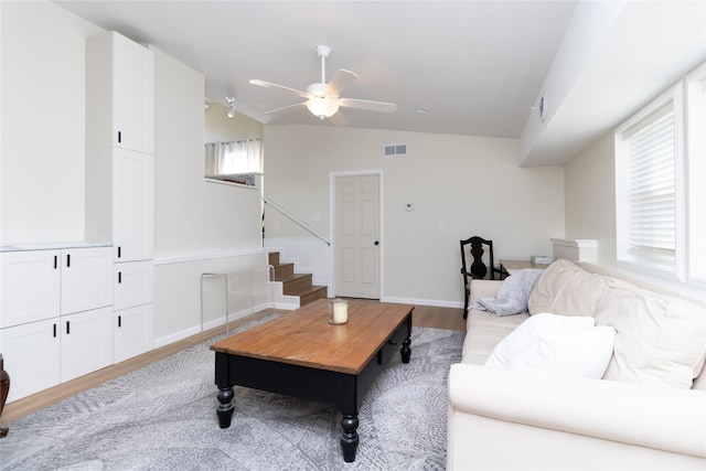 living room with vaulted ceiling, ceiling fan, and light wood-type flooring