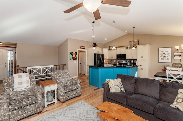 living room with light hardwood / wood-style flooring, vaulted ceiling, and ceiling fan