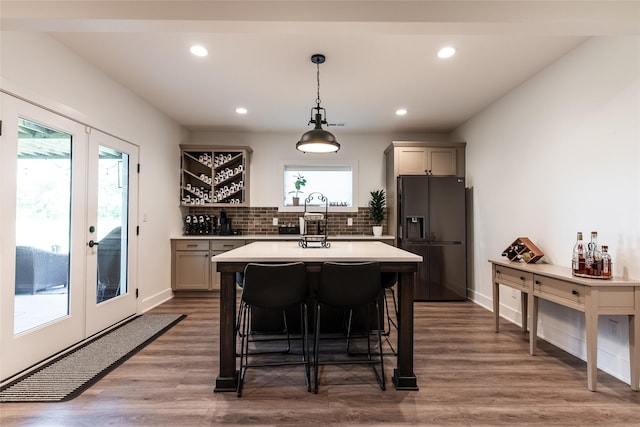 kitchen featuring hardwood / wood-style floors, pendant lighting, backsplash, plenty of natural light, and black refrigerator with ice dispenser