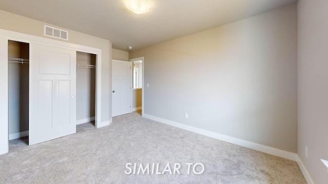 unfurnished bedroom featuring light carpet and a closet