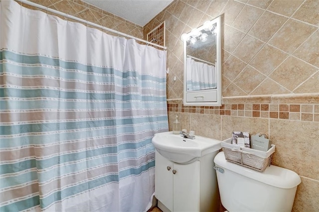 bathroom featuring vanity, toilet, and tile walls