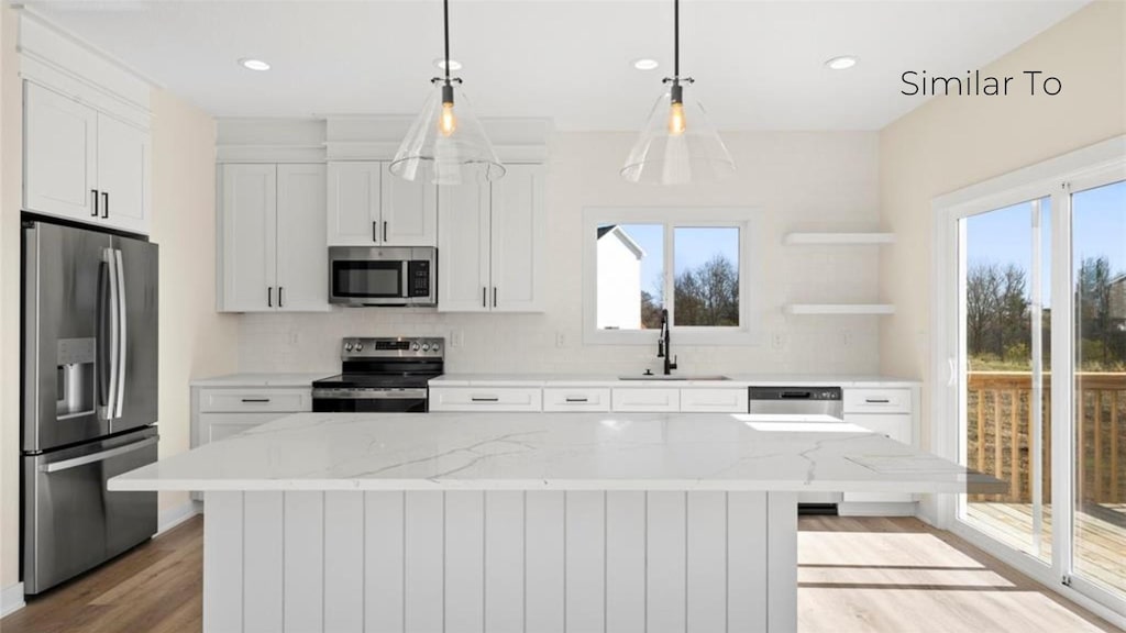 kitchen featuring a kitchen island, appliances with stainless steel finishes, sink, and light stone counters