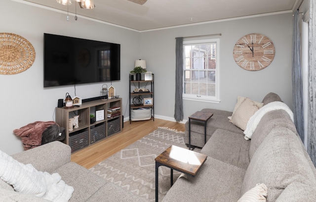 living room with wood-type flooring, ornamental molding, and ceiling fan