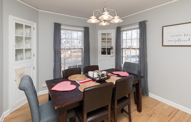 dining room with ornamental molding, light wood-type flooring, and built in shelves