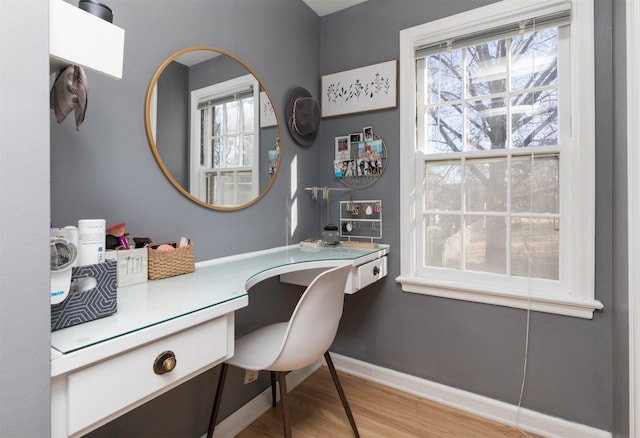 home office with built in desk and light hardwood / wood-style flooring