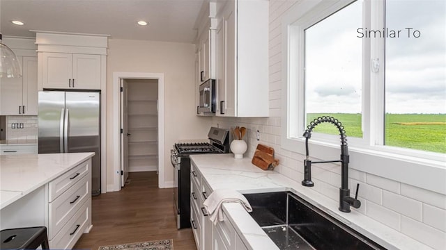 kitchen featuring appliances with stainless steel finishes, light stone countertops, and white cabinets