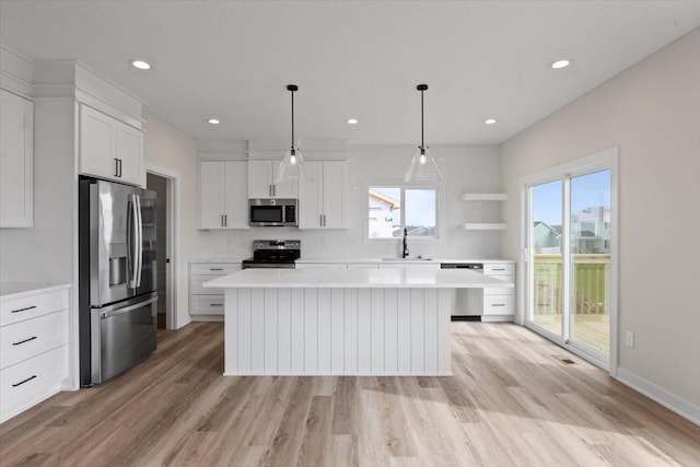 575 NW Prairie Rose Ln, Waukee, IA 50263 - kitchen with appliances with stainless steel finishes, light wood finished floors, a kitchen island, white cabinets, and light countertops