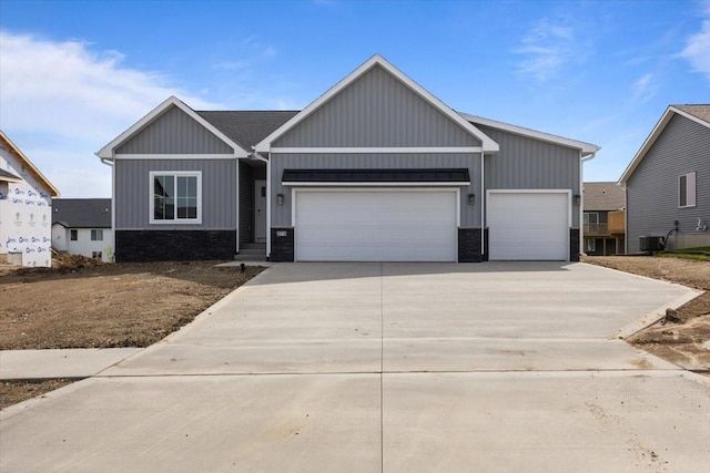 575 NW Prairie Rose Ln, Waukee, IA 50263 - view of front facade with an attached garage, concrete driveway, stone siding, central air condition unit, and board and batten siding