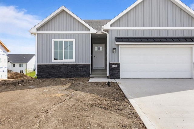 575 NW Prairie Rose Ln, Waukee, IA 50263 - view of front of property featuring stone siding, board and batten siding, a garage, and concrete driveway