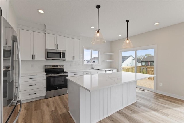 575 NW Prairie Rose Ln, Waukee, IA 50263 - kitchen with appliances with stainless steel finishes, a sink, light wood-style floors, decorative backsplash, and plenty of natural light