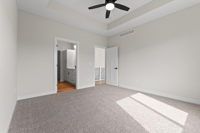 575 NW Prairie Rose Ln, Waukee, IA 50263 - unfurnished bedroom featuring carpet floors, baseboards, a tray ceiling, and ensuite bathroom