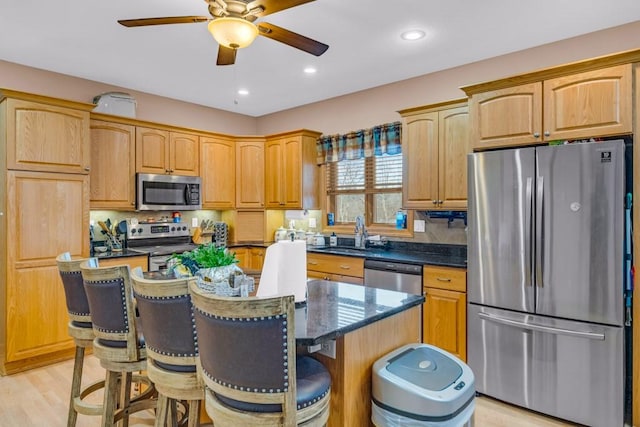 kitchen with a kitchen island, appliances with stainless steel finishes, sink, and a kitchen bar