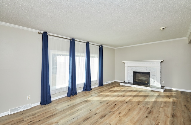 unfurnished living room featuring crown molding, a textured ceiling, a fireplace, and light wood-type flooring