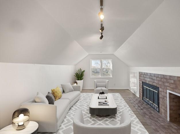 living room featuring track lighting, lofted ceiling, and a fireplace