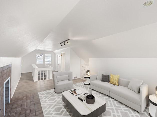 living room with hardwood / wood-style flooring, track lighting, and vaulted ceiling