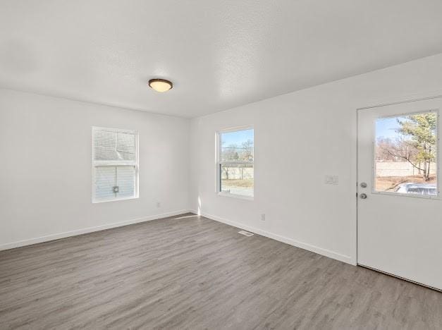 empty room with hardwood / wood-style flooring and a healthy amount of sunlight