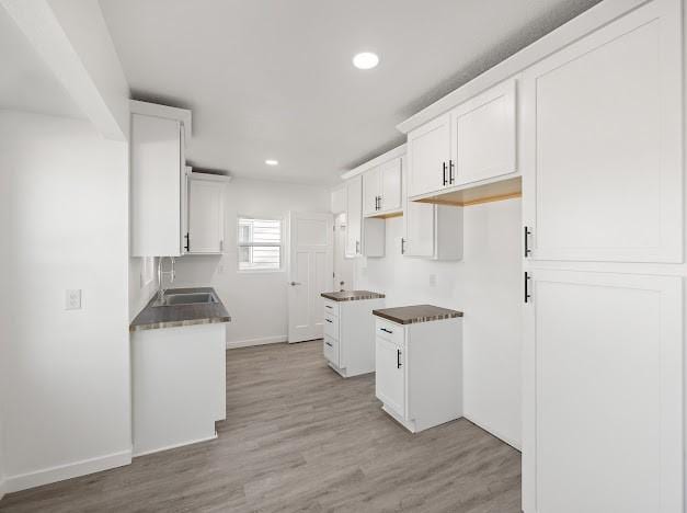 kitchen featuring white cabinetry, sink, and light hardwood / wood-style flooring