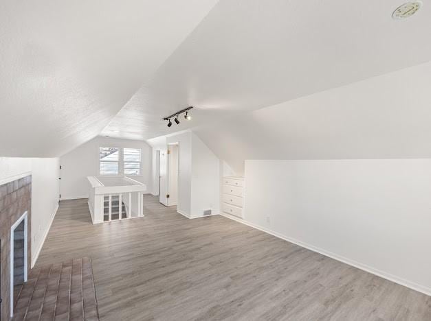 bonus room with hardwood / wood-style flooring, lofted ceiling, and a textured ceiling