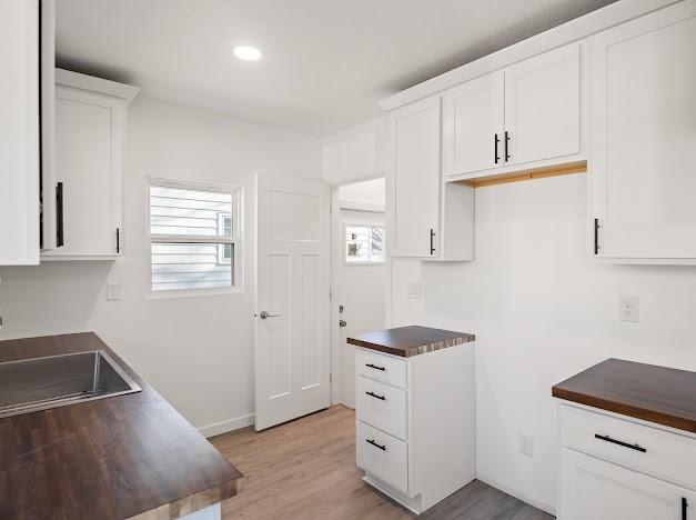 kitchen with white cabinetry, sink, and light hardwood / wood-style flooring