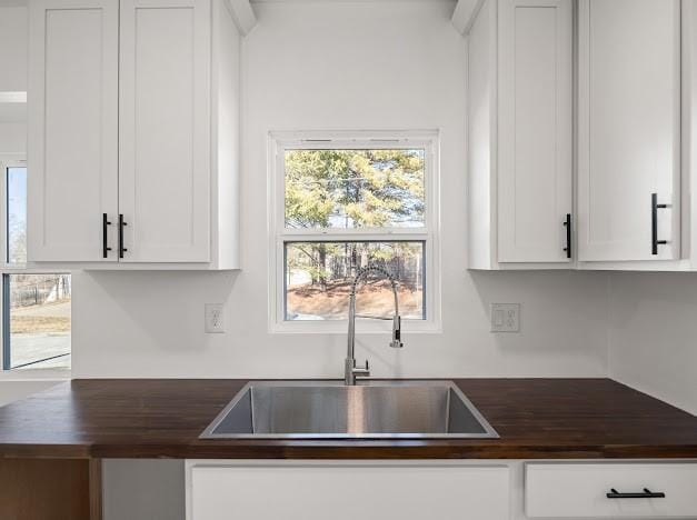 kitchen with white cabinetry, butcher block counters, and sink