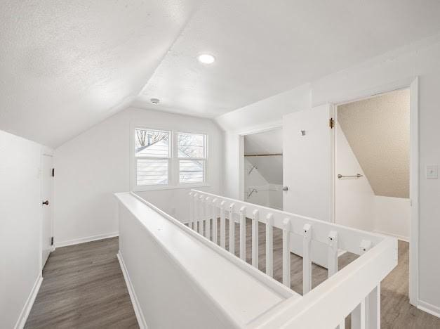 corridor with lofted ceiling, dark hardwood / wood-style floors, and a textured ceiling