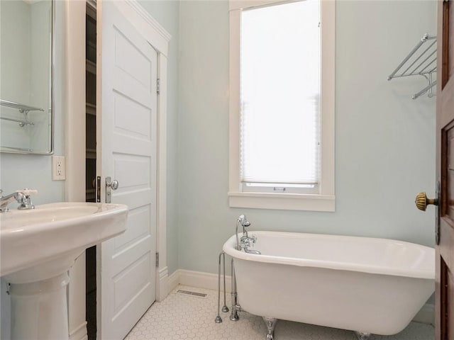 bathroom featuring a tub to relax in, tile patterned floors, and sink