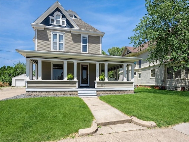 view of front of house featuring an outbuilding, a garage, a front lawn, and covered porch