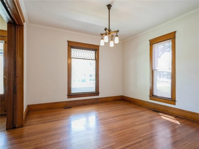 spare room featuring a notable chandelier, ornamental molding, and hardwood / wood-style floors