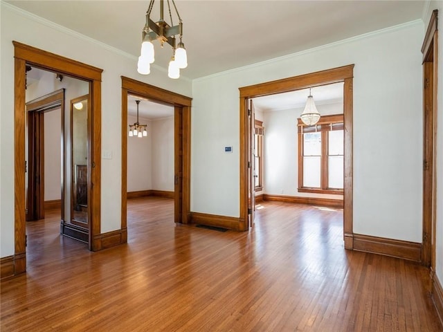 unfurnished room featuring a notable chandelier, ornamental molding, and hardwood / wood-style floors