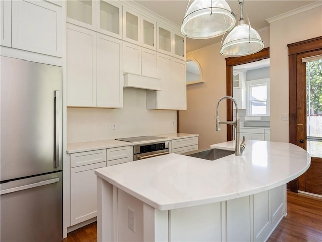 kitchen with pendant lighting, stainless steel appliances, white cabinets, and a center island with sink