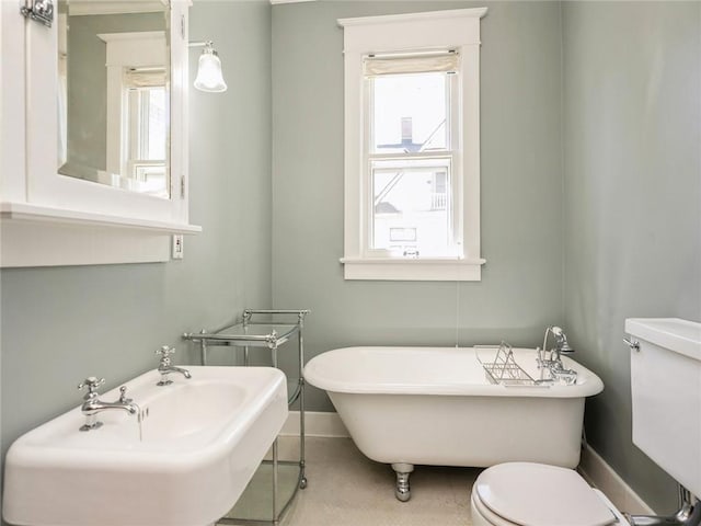 bathroom featuring toilet, a bath, sink, and a wealth of natural light