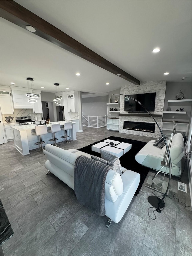 living room featuring a stone fireplace and beamed ceiling