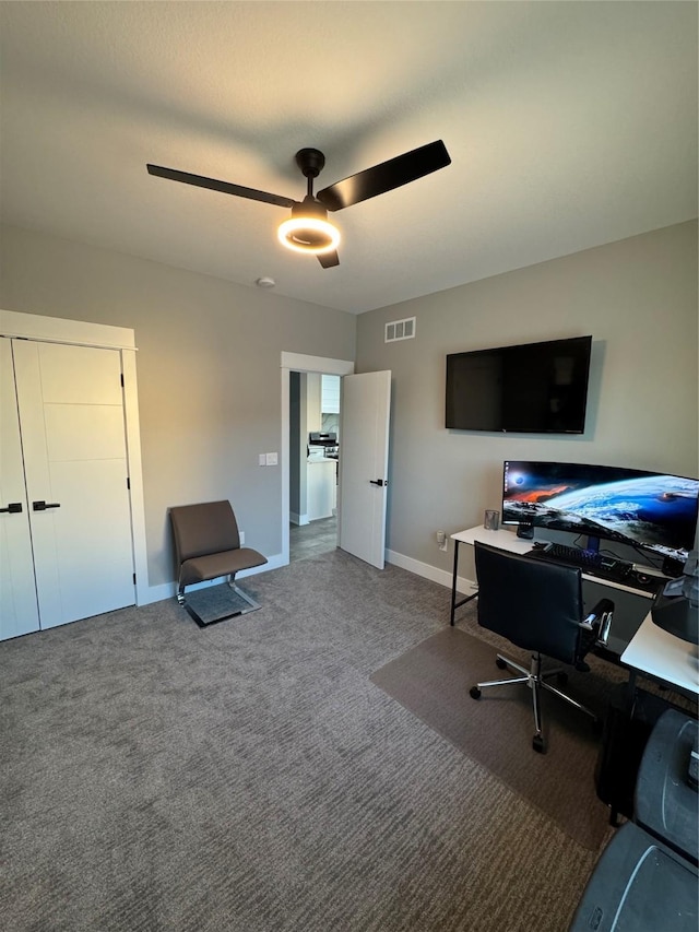 carpeted home office featuring ceiling fan