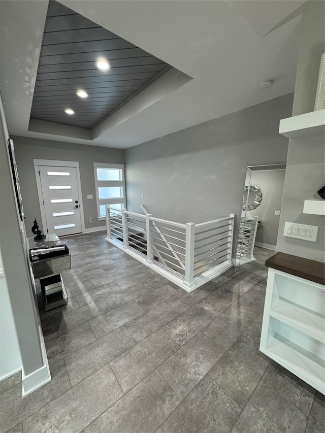 hallway with a raised ceiling and wooden ceiling