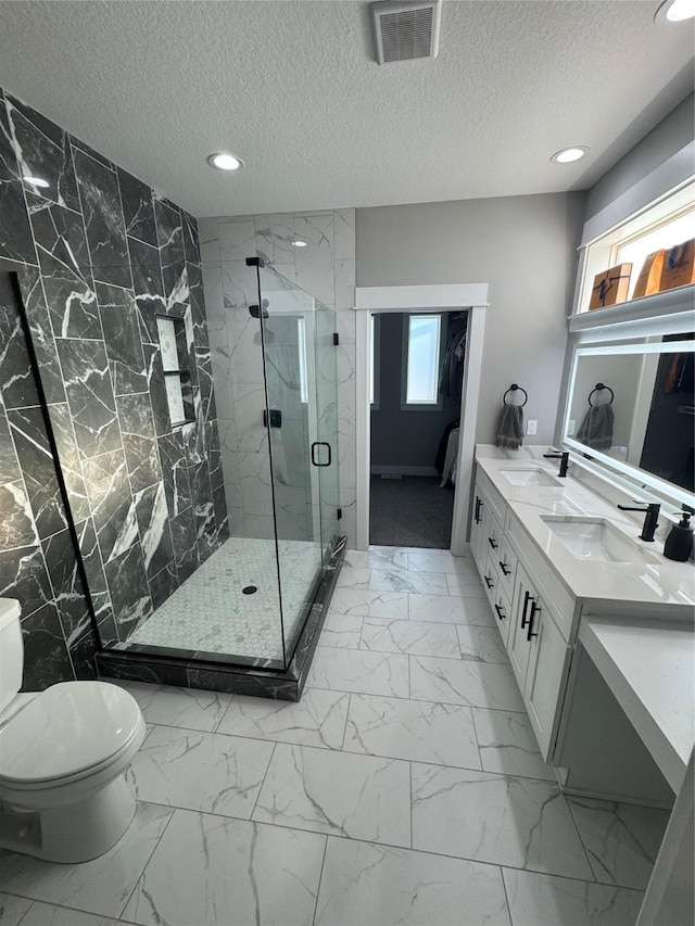 bathroom featuring vanity, toilet, a shower with door, and a textured ceiling