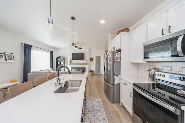 kitchen with appliances with stainless steel finishes, decorative light fixtures, sink, and white cabinets